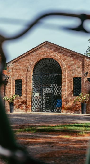 Edificio in mattoni con portone in ferro, circondato da piante in vasi.